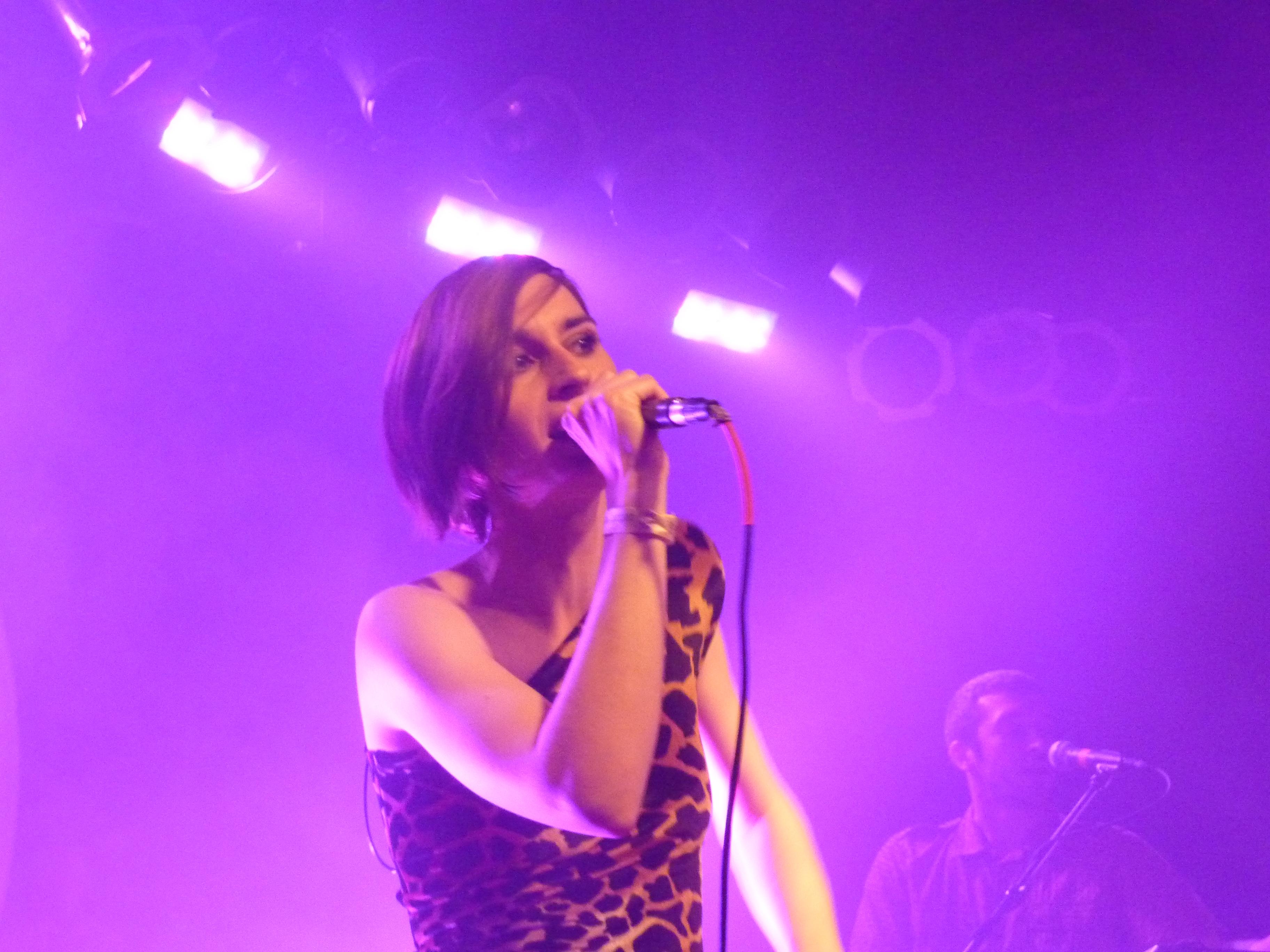 A woman sings while holding a microphone.