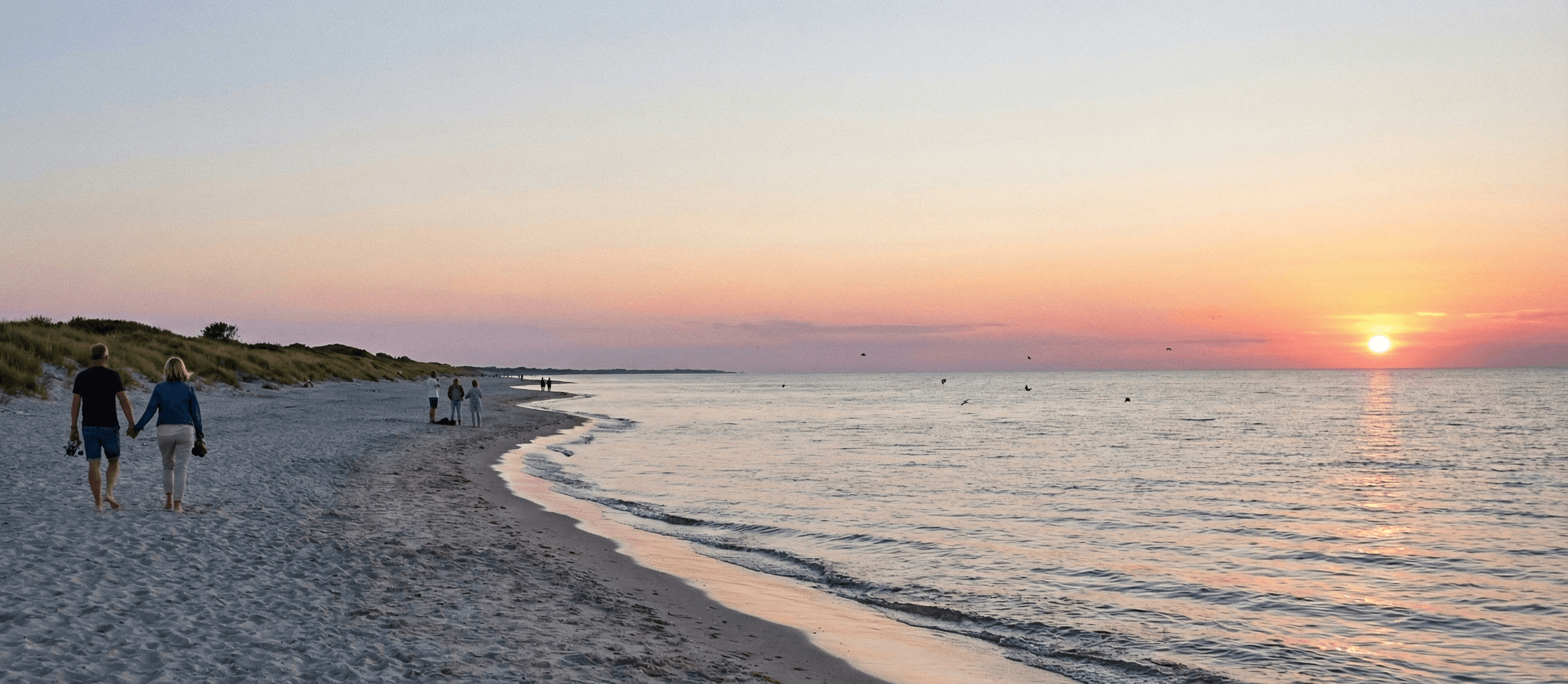 A beach at sunset with people in the distance.