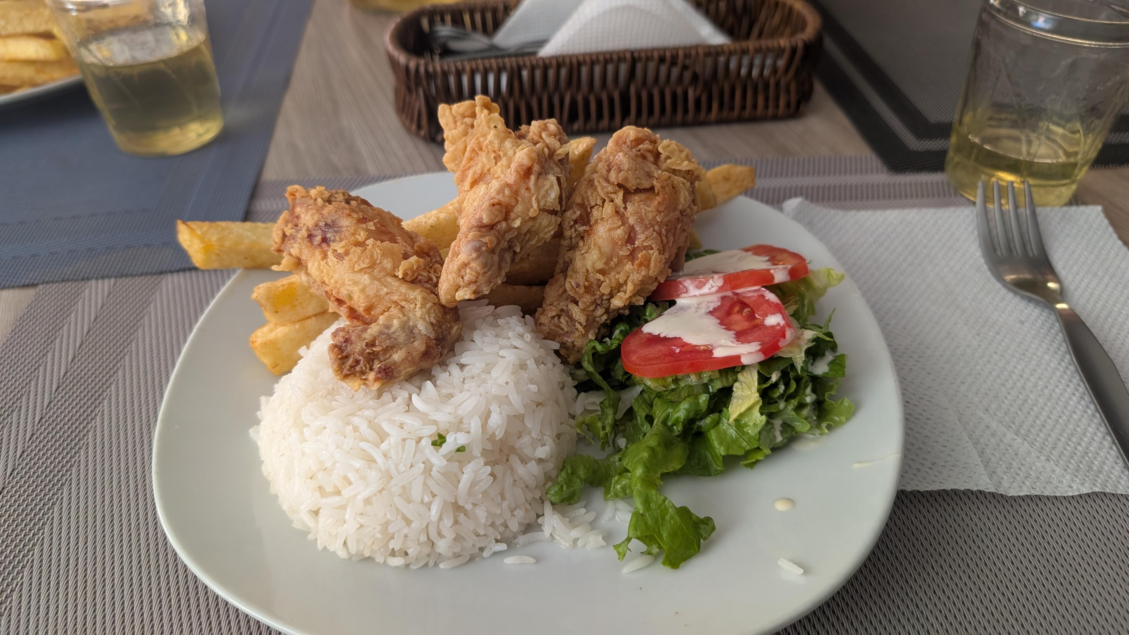 A plate of fried chicken, rice, and salad.