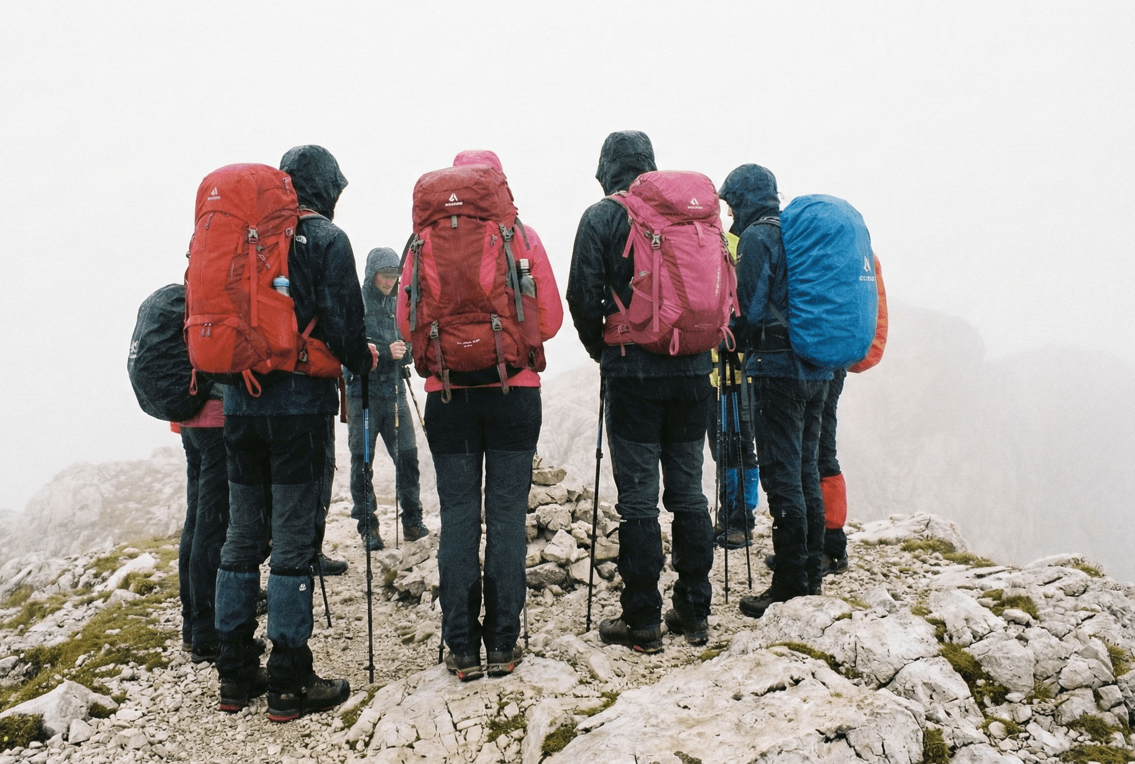 A group of hikers stands on a foggy mountain.