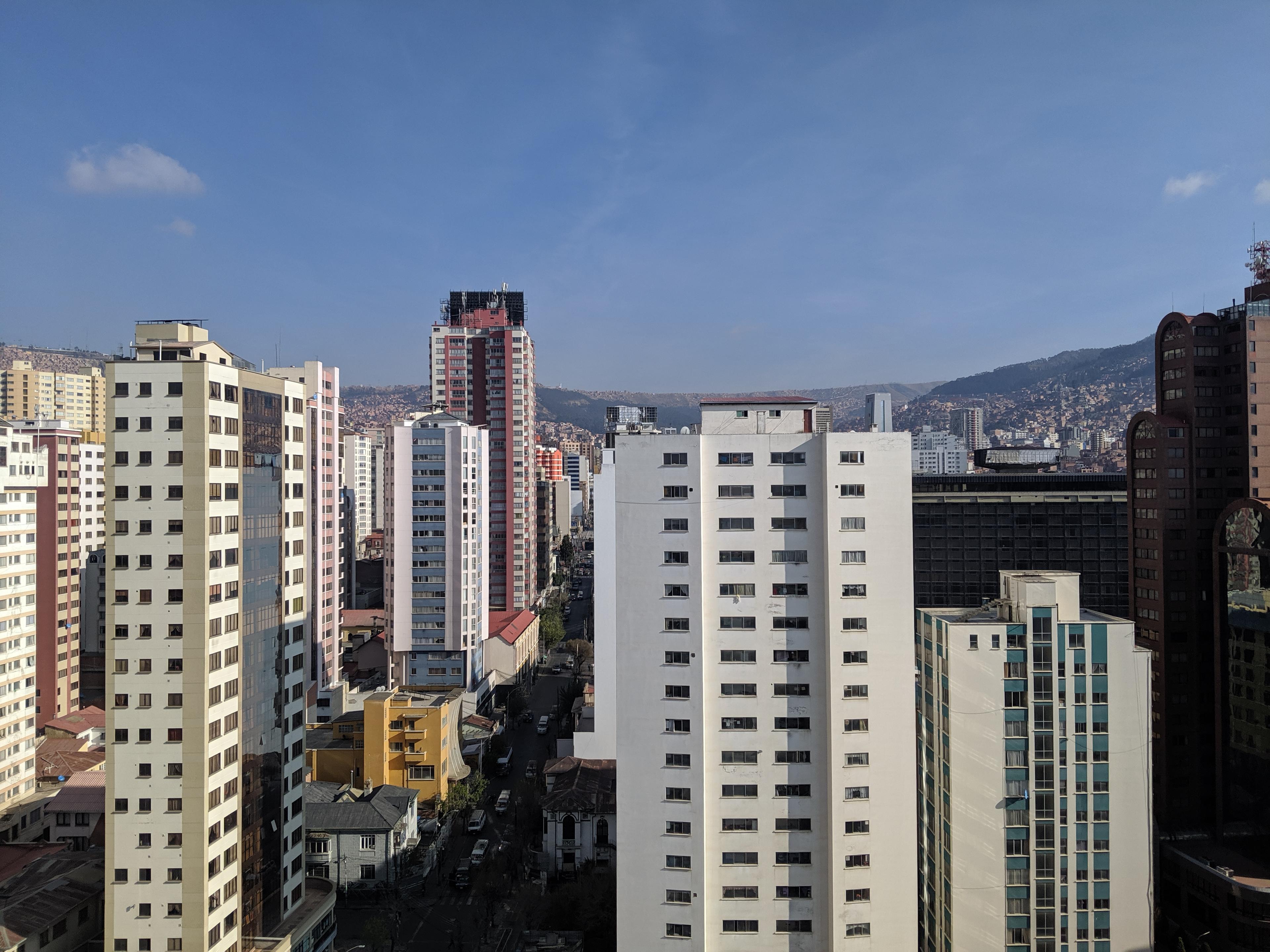 A city skyline with shallow mountains in the background.