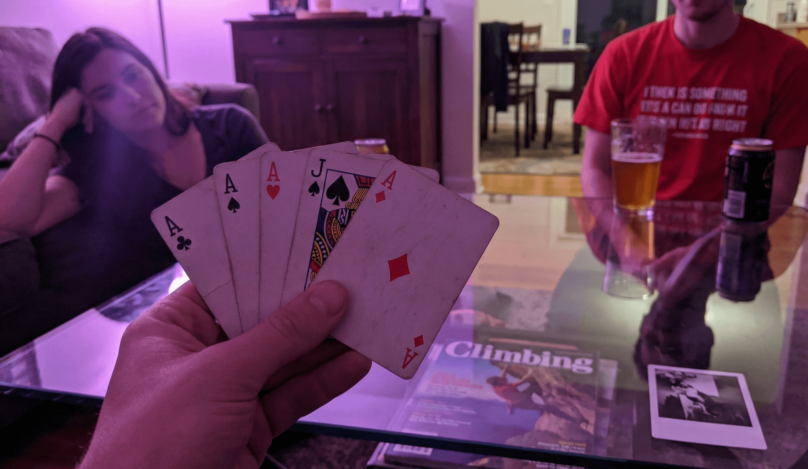 A hand holds cards at a living room coffee table.