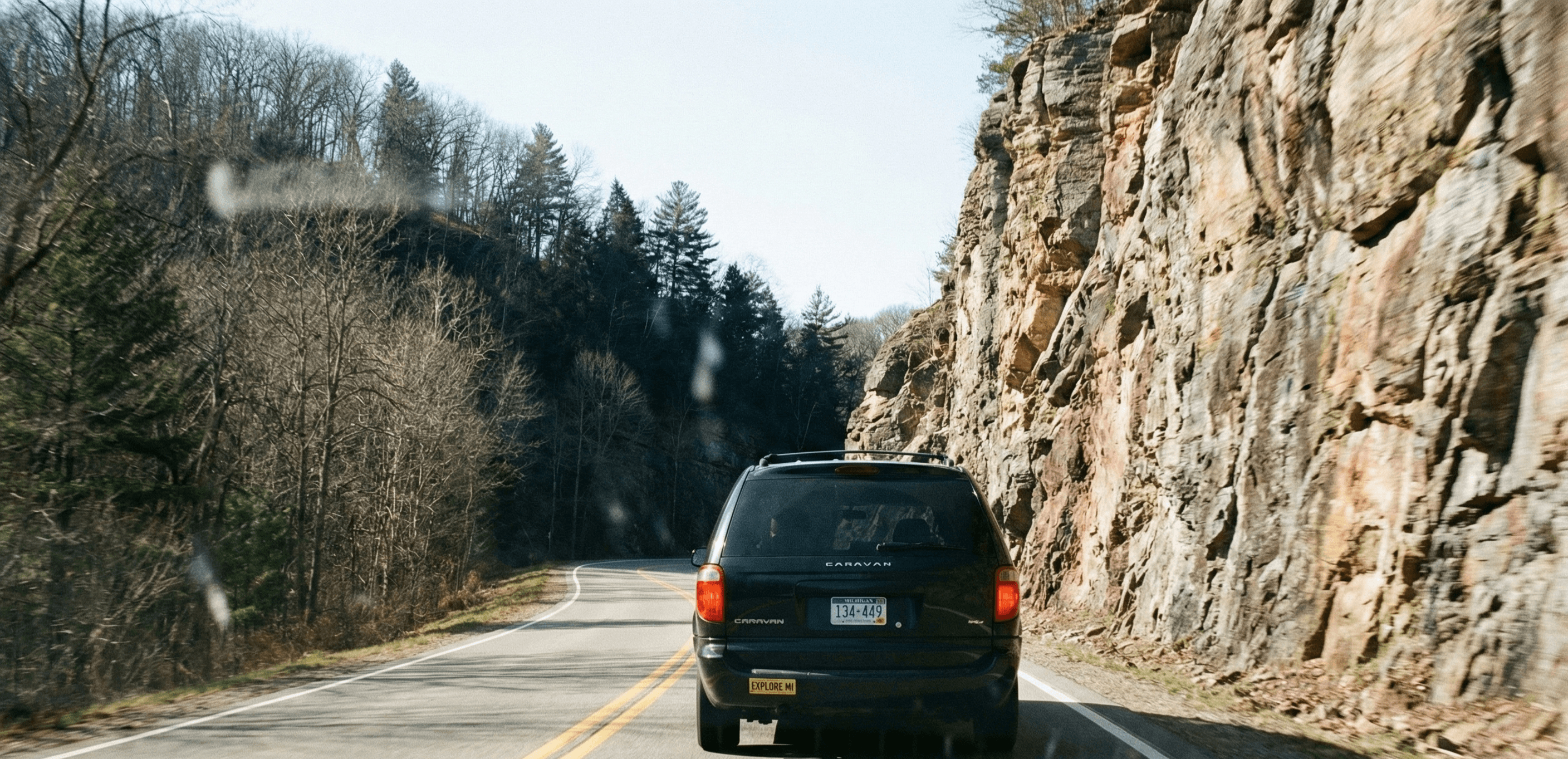 A rear view of a van driving on a road.